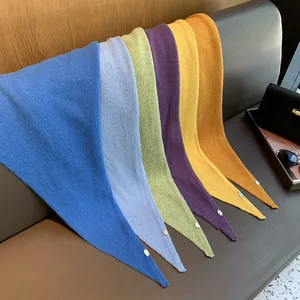 Mehrfarbige Strickschals aus 100% Wolle, gefaltet auf einem grauen Ledersofa im Raum