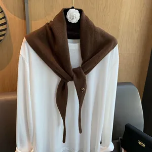 Detailaufnahme von Woll-Dreieckstuch mit Bernstein-Knopf auf weißem Shirt