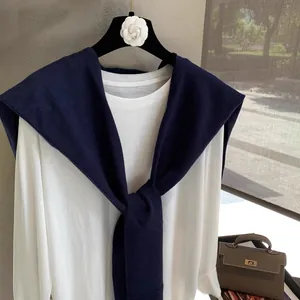 Women's white long-sleeve T-shirt paired with a dark blue knitted shawl wrap