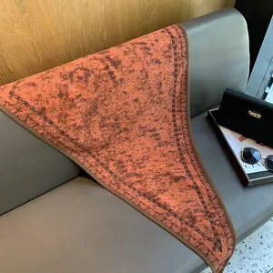 Detail of vintage paisley pattern and caramel orange texture on a premium triangle shawl