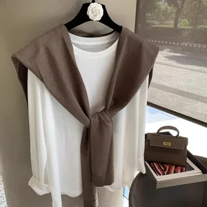 Detailed close-up of dark coffee knitted shawl over white long sleeve tee for women