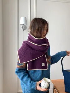 Détail d'une écharpe en laine violette avec bordure blanche contrastée et maille côtelée