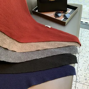 Close-up of stacked wool knit scarves showing the soft 100% wool texture and logo label