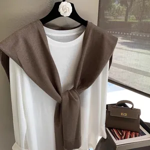 Detailed knit texture of a brown shawl layered over a white long sleeve tee