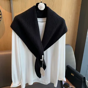 Detail der Strickstruktur des schwarzen Dreieckschals über einem weißen Baumwolltop