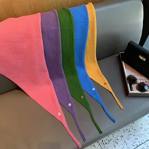 Nahaufnahme von Strickschals in kräftigen Farben mit goldenen Logo-Anhängern