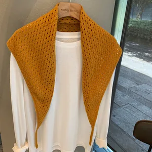 Détail du châle en laine tricotée jaune superposé sur un t-shirt blanc à manches longues