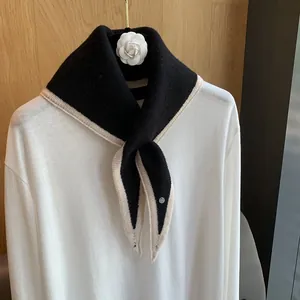Detail shot of the knitted texture and white contrast trim on a black triangular scarf