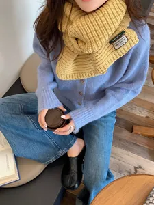 Detail showing bright yellow chunky knit scarf paired with light blue cardigan and denim