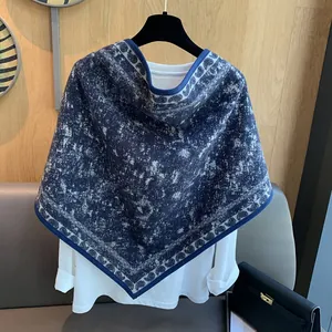 Detail view of a navy blue printed triangle shawl with marble texture on a white shirt