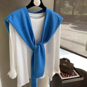 Detail of a cobalt blue knit shawl draped over a classic white long sleeve t-shirt
