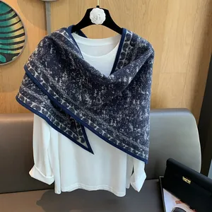 Detail of navy blue and white knit shawl with ethnic trim on a white garment