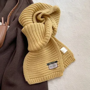Detail of mustard yellow chunky knit scarf showing wool blend texture and design label