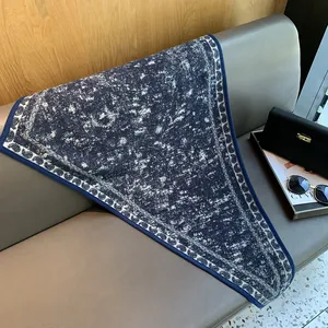 Detail of navy blue triangle shawl with paisley trim and snowy texture on leather seat