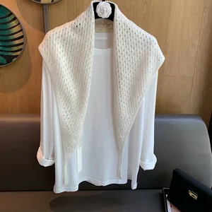 Détail d'un châle blanc en laine tricoté avec un motif délicat de losanges ajourés