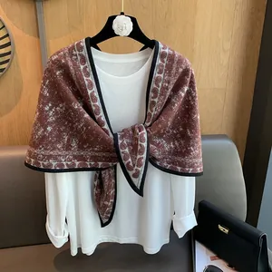 Detail of vintage paisley shawl with contrast black trim draped on a white long sleeve shirt