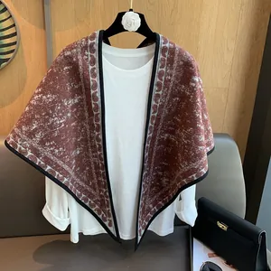 Detail of vintage knit triangle shawl with retro floral patterns on a display hanger