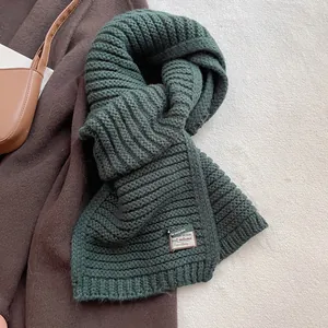 Detailed close-up of dark green wool blend scarf with a decorative woven label