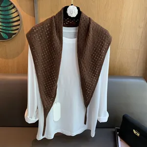 Détail du châle en laine ajouré marron foncé porté sur un t-shirt blanc à manches longues