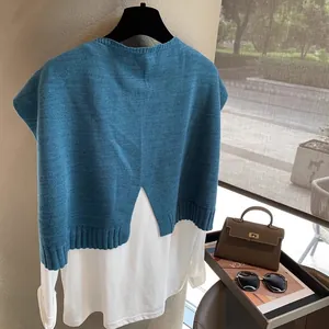 Detail of blue wool knit vest over white long sleeve shirt with back slit design