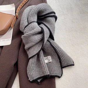 Détail de l'écharpe en laine grise avec bordure noire contrastée sur manteau brun