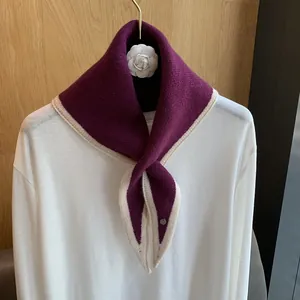 Detail of burgundy knitted triangle scarf with ivory stripes on a white shirt