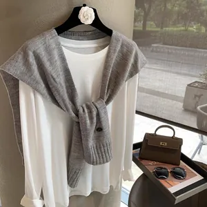 Close-up of stylish grey wool knit shawl layered over a white long-sleeve cotton T-shirt