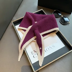 Detail of soft purple and beige knit scarf featuring a silver logo tag and premium texture