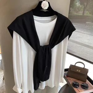 Detail of a chic black wool knit shawl layered over a white long-sleeve cotton T-shirt