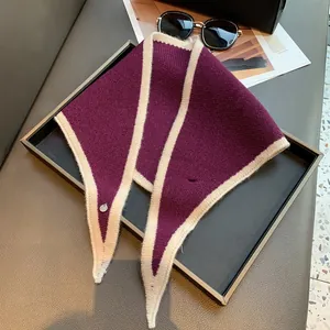 Close-up of a purple knitted triangular scarf with silver logo on a lifestyle background