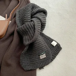 Detail of wool blend knitted scarf texture showing material label and stitching