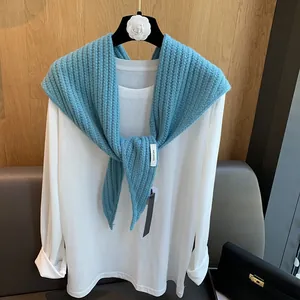 Détail de la texture en maille côtelée bleue et de l'étiquette 100% laine du châle
