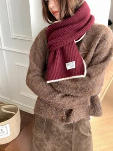 Détail de l'écharpe en maille bordeaux avec bordure beige contrastée et étiquette de marque