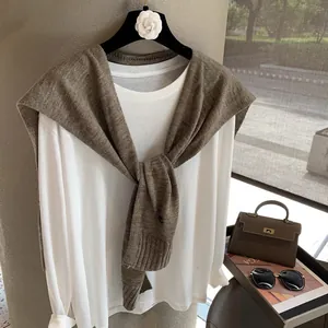Close-up of stylish white cotton long sleeve top paired with brown knit wool shawl