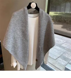 Close-up of grey wool blend knitted shawl texture with a premium brown leather label
