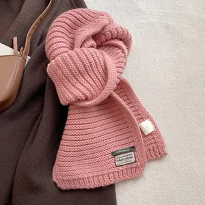 Detail of pink wool blend chunky knit scarf featuring a brand label and material tag