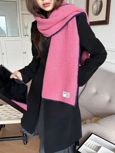 Détail de l'écharpe en maille rose vif montrant la texture côtelée et le liseré bleu marine
