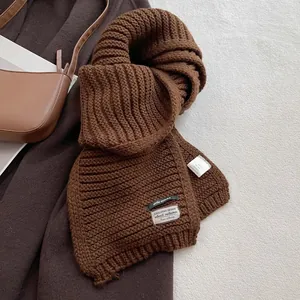 Detailed macro view of the thick knit texture and brown wool blend scarf with labels