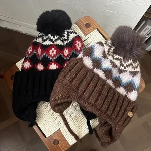 Λεπτομέρεια από πλεκτούς σκούφους Fair Isle με χοντρή μάλλινη υφή και διακοσμητικά πομ-πόμ