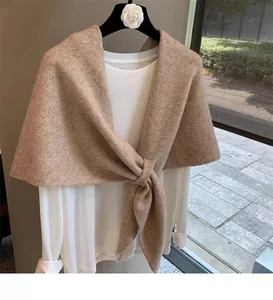 Detail of camel wool blend knit shawl over a white shirt with an elegant knot design