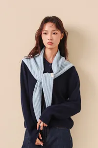 Détail d'une écharpe en tricot à rayures bleues avec étiquette sur un cardigan marine