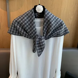 Detailed close-up of retro plaid scarf showing woven texture and hemmed edges on a hanger