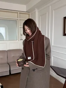 Détail de l'écharpe en maille de laine avec bord contrasté et étiquette sur manteau
