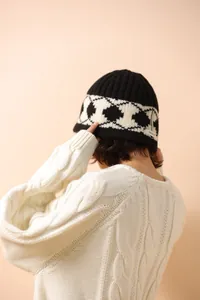 Detailed close-up of 100% wool knit hat featuring black and white diamond pattern