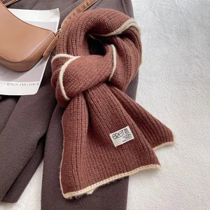 Détail de la maille d'une écharpe en laine marron avec bordure contrastée blanche chic