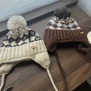 Λεπτομέρεια από πλεκτούς σκούφους Fair Isle με γούνινα πον πον και καλύμματα αυτιών