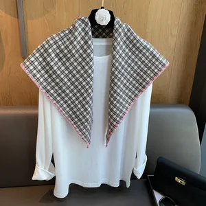 Plaid knitted triangle scarf with pink hand-stitched edges over white long sleeve shirt