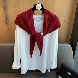 Détail d'un châle en laine rouge à motif arête de poisson avec un haut blanc classique