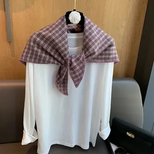 Detail of vintage plaid triangle scarf with purple edge over white long-sleeved shirt
