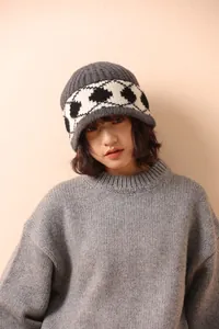 Detailed texture of thick grey wool knit hat with retro black and white diamond pattern